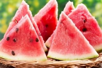A bottle of watermelon seed oil with watermelon slices and seeds in the background.
