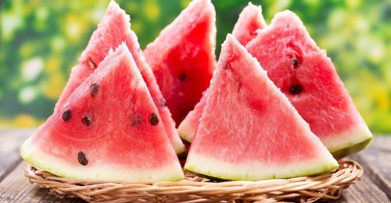 A bottle of watermelon seed oil with watermelon slices and seeds in the background.